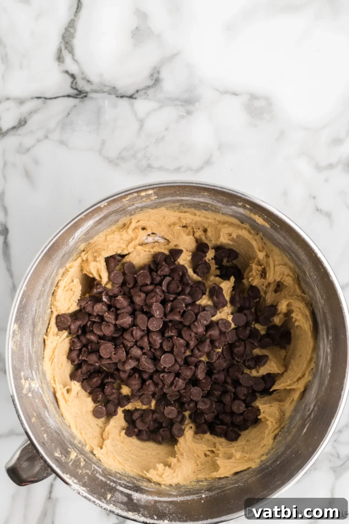 Mrs. Fields' Legendary Chocolate Chip Cookies 7 Semi-sweet chocolate chips being gently folded into cookie dough in a mixing bowl.