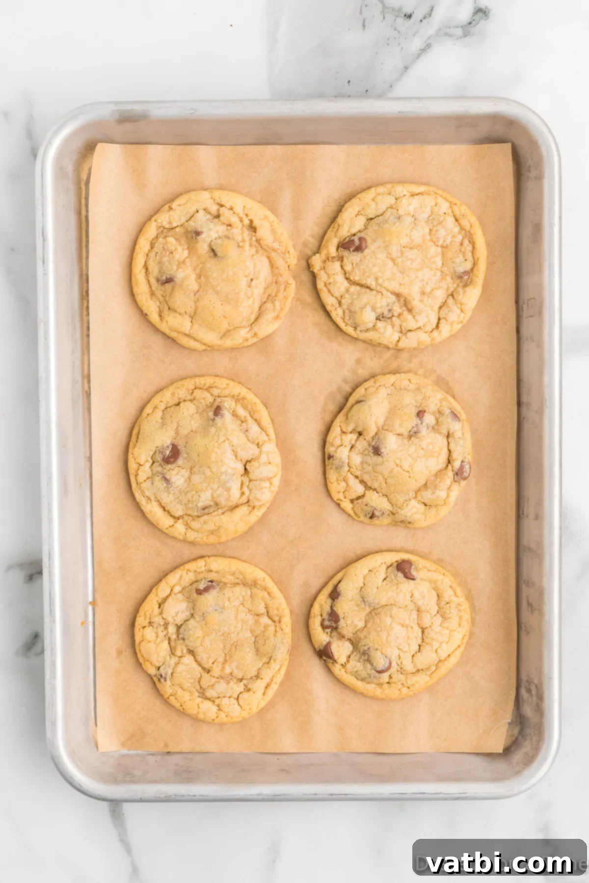 Mrs. Fields' Legendary Chocolate Chip Cookies 9 Freshly baked Mrs. Fields style chocolate chip cookies cooling on a baking sheet, showing golden edges and soft centers.