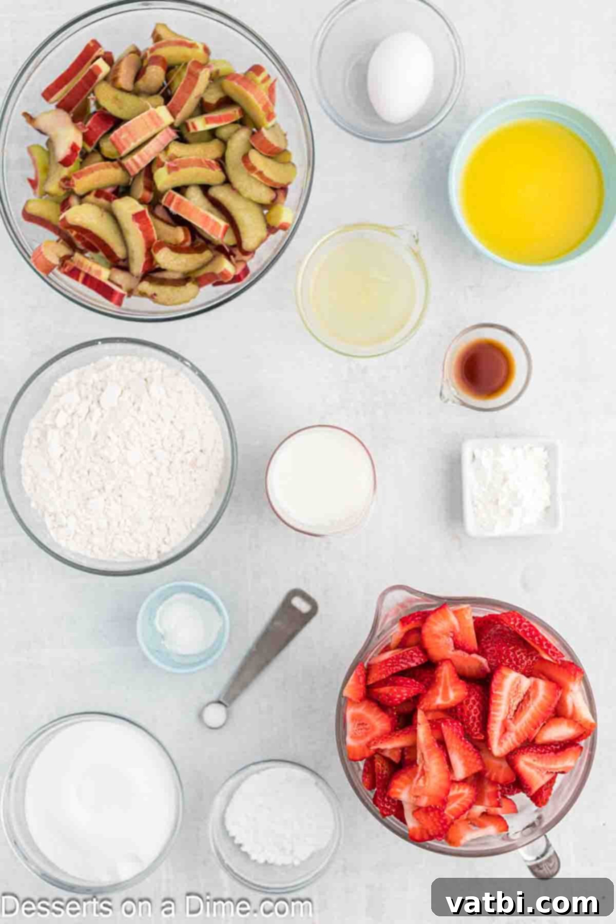 Sun-Kissed Strawberry Rhubarb Cobbler 3 A vibrant display of fresh ingredients laid out for Strawberry Rhubarb Cobbler, featuring freshly chopped rhubarb stalks, bright red strawberries, a bowl of granulated sugar, a cut lemon, a small pile of cornstarch, flour, a stick of butter, a pinch of salt, and a spoon of baking powder.