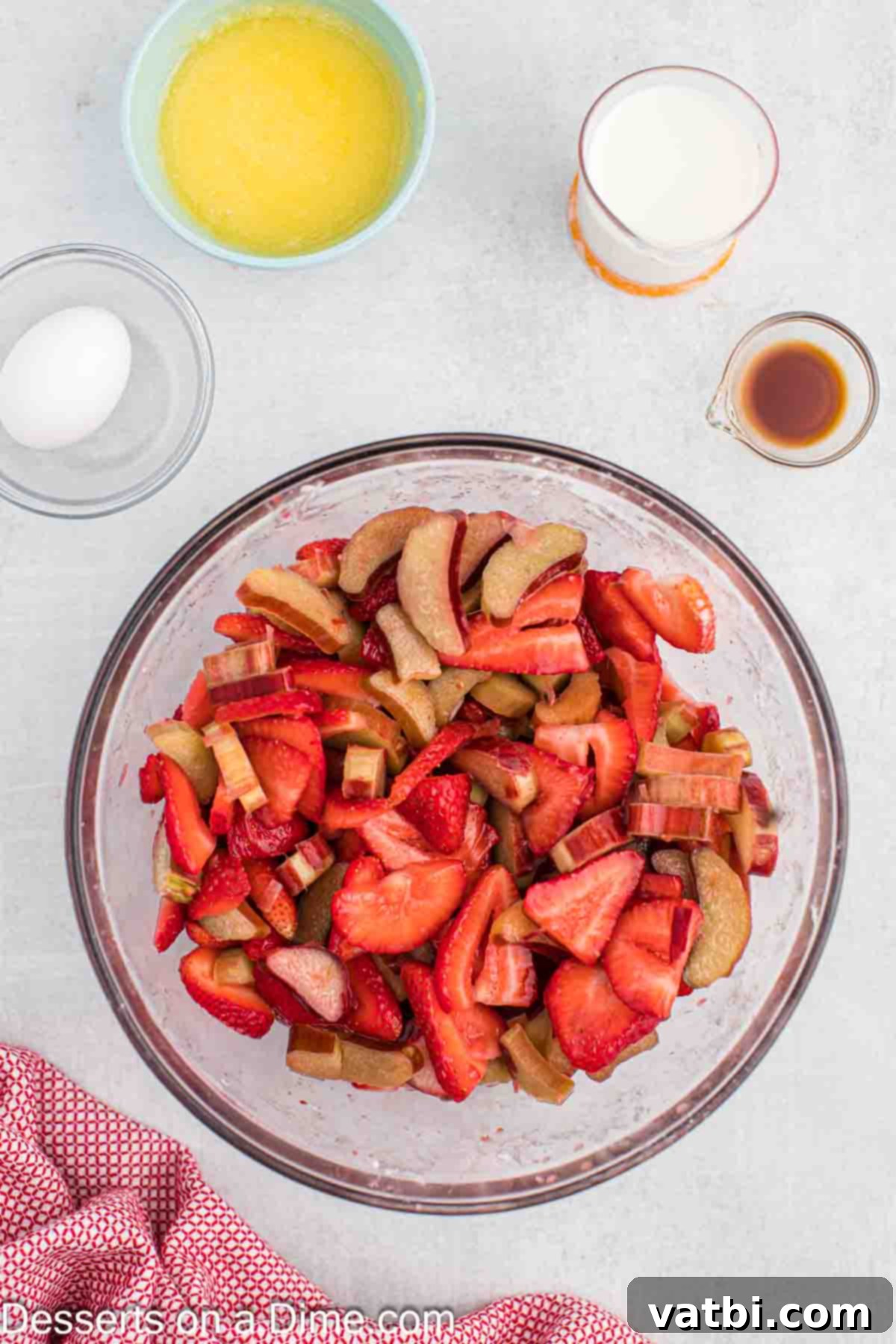 Sun-Kissed Strawberry Rhubarb Cobbler 4 A medium mixing bowl filled with a colorful blend of chopped rhubarb, diced strawberries, granulated sugar, lemon juice, and cornstarch, ready to be mixed for the cobbler filling.