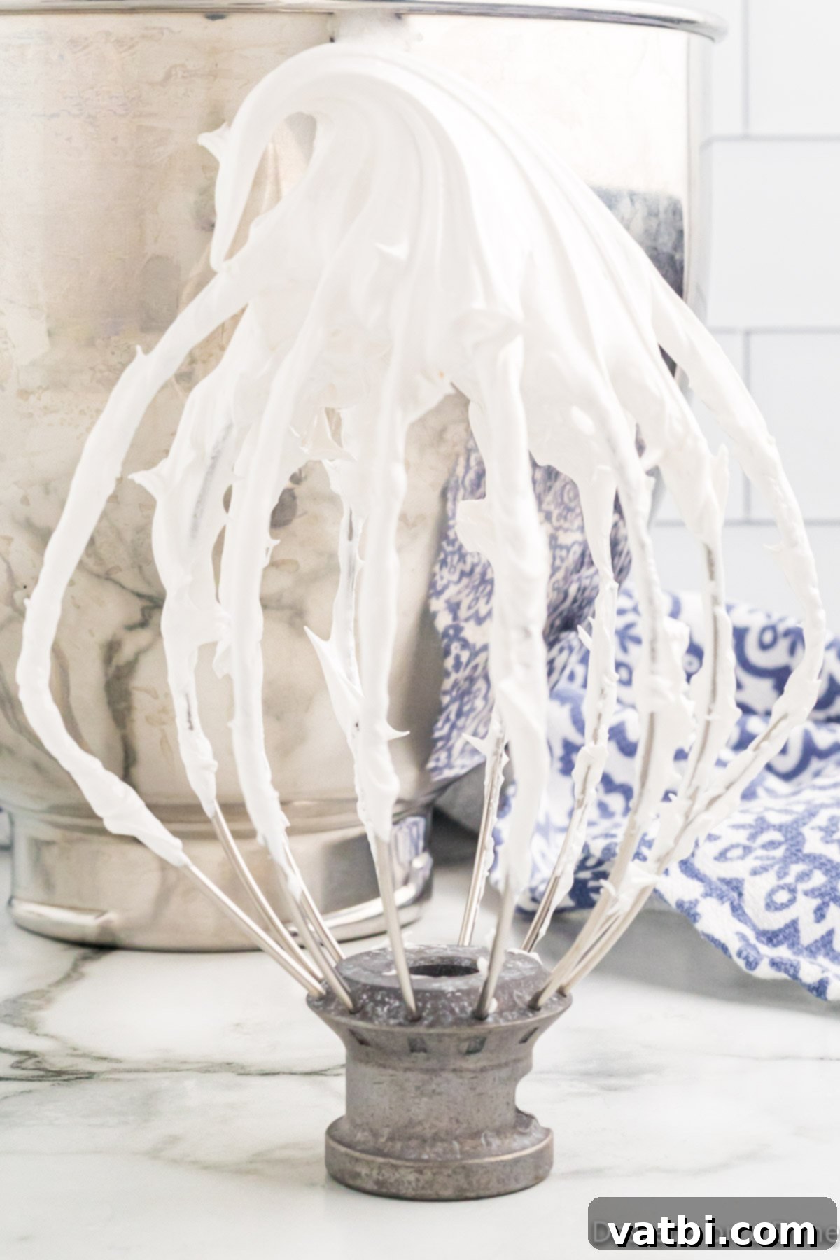 Cloud-Soft Homemade Marshmallow Fluff 8 A stand mixer whisk attachment coated in glossy, white homemade marshmallow cream.