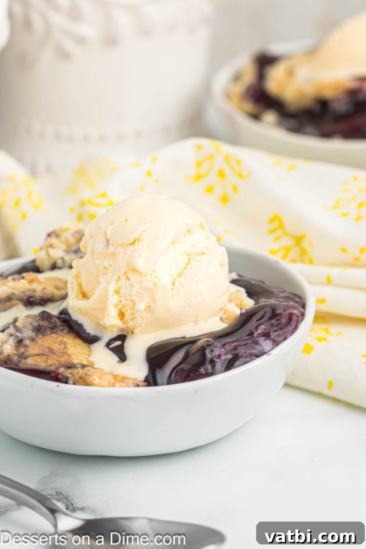 Easy Blueberry Dump Cake 2 Blueberry dump cake topped with vanilla ice cream in a bowl