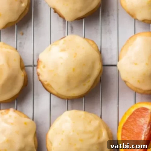 Zesty Delights 17 Delightful Iced Orange Cookies with orange glaze on a cooling rack, showing hints of zest.
