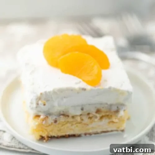 Zesty Delights 4 A slice of light and airy Mandarin Orange Angel Food Cake on a white plate, topped with whipped cream.