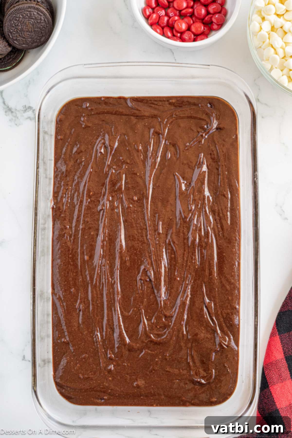Grinch's Festive Fudgies 5 Brownie batter evenly spread in a baking pan, ready for the oven.