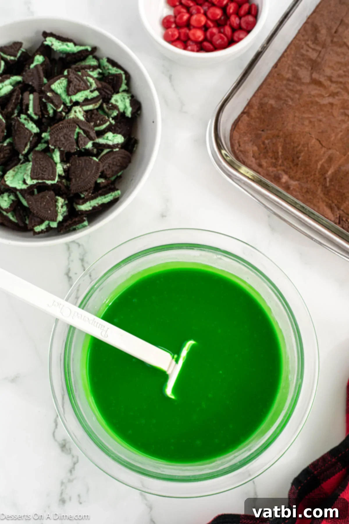 Grinch's Festive Fudgies 8 Green gel food coloring being stirred into melted white chocolate mixture.