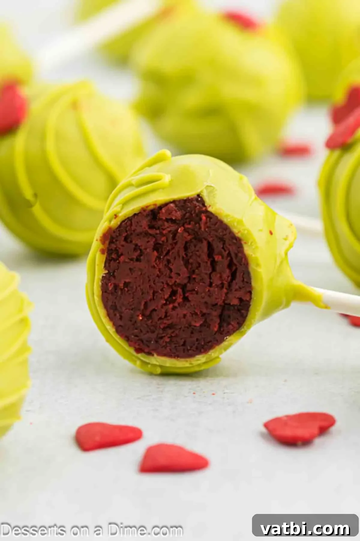 Whoville Grinch Cake Pops 12 Grinch Cake Pops up close, showing the detail of the green coating and red heart.