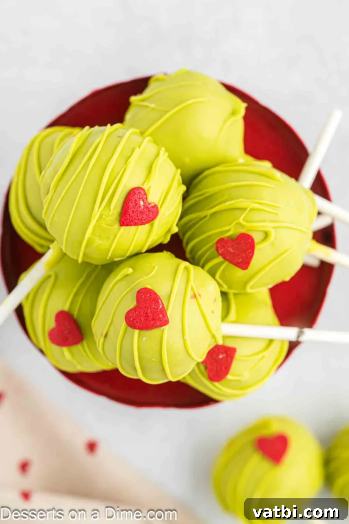 Whoville Grinch Cake Pops 13 Grinch Cake Pops arranged on a festive platter, ready for serving.