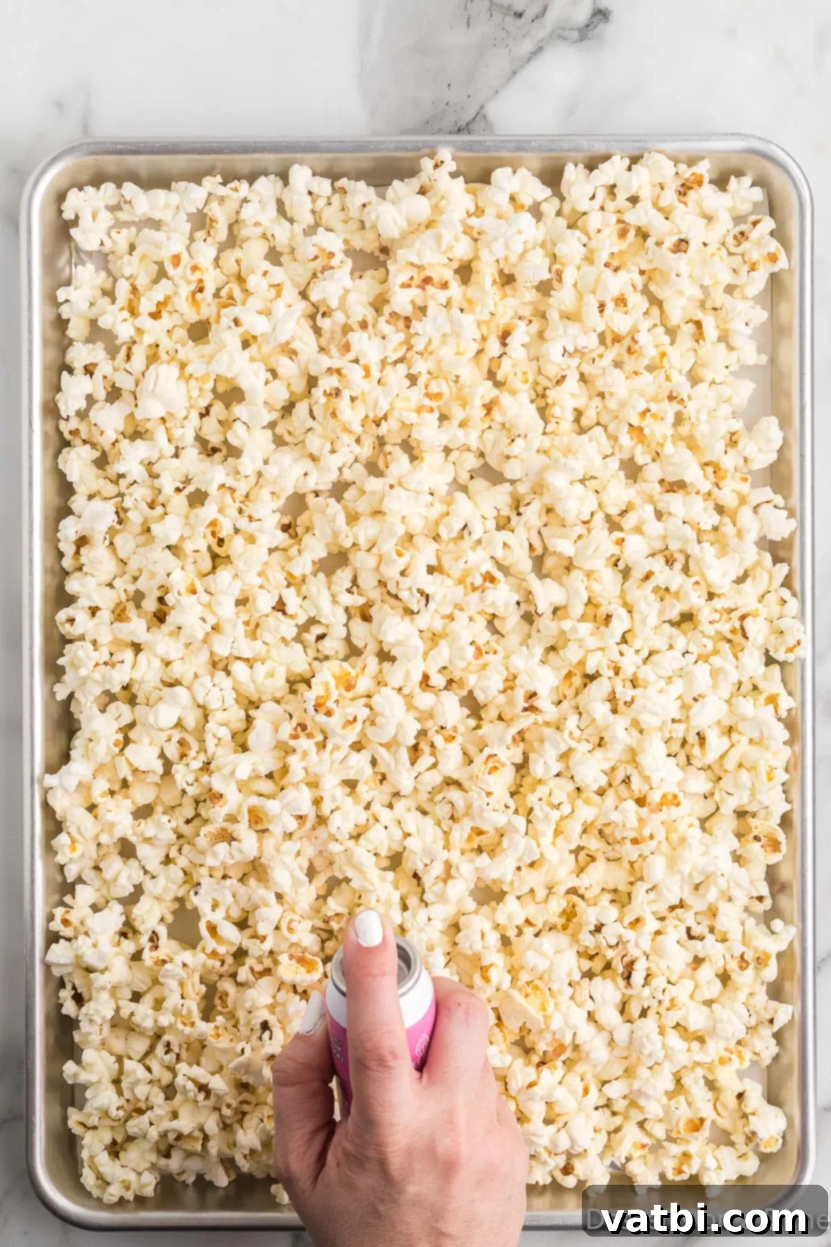 Rainbow Unicorn Popcorn 4 Popped popcorn spread out on a baking sheet, ready for coating.
