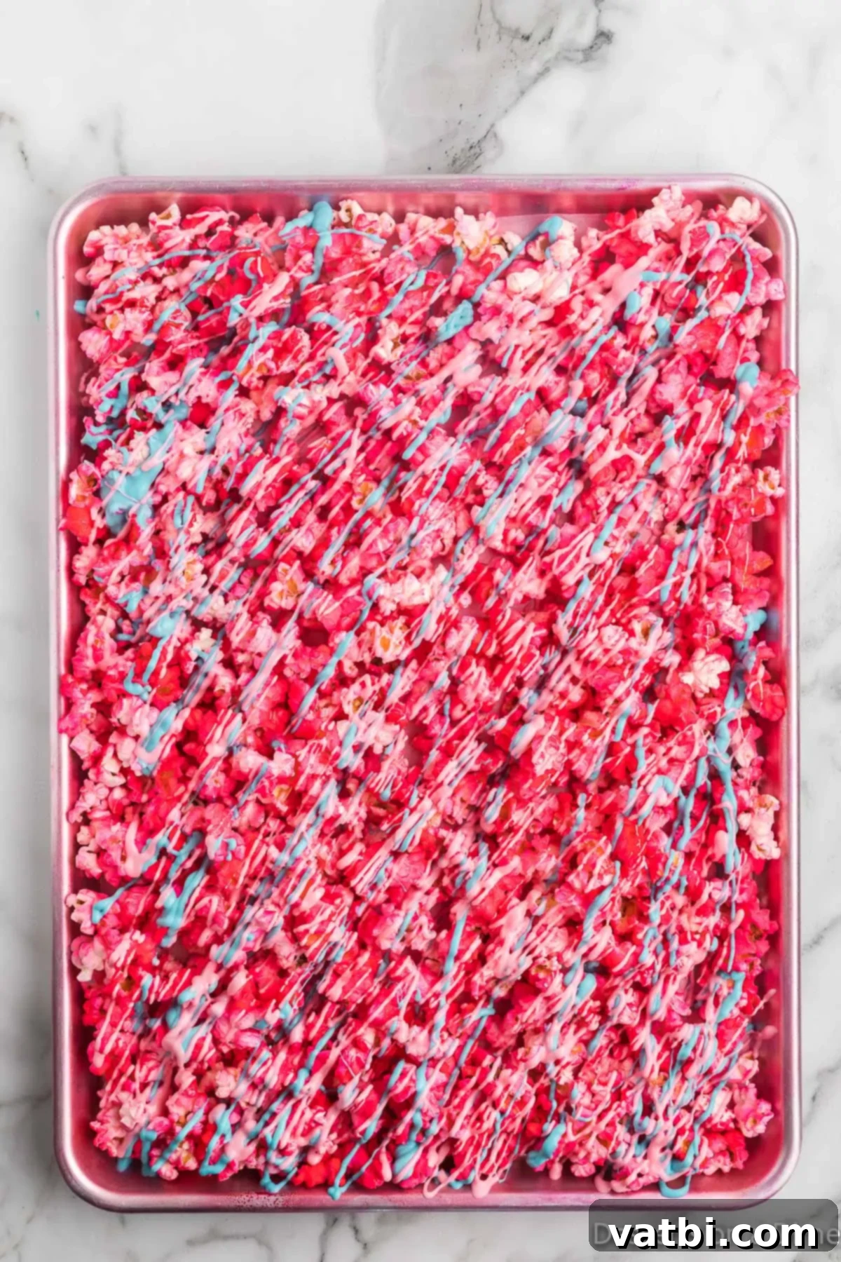 Rainbow Unicorn Popcorn 7 Melted candy melts in pink, blue, and purple drizzled artfully over the prepared popcorn, followed by rainbow sprinkles.