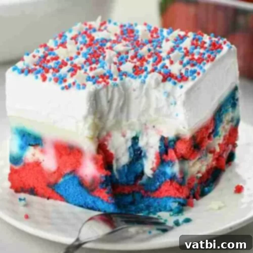 A slice of Patriotic Poke Cake with red, white, and blue layers.
