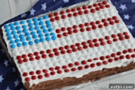 A large American Flag Cookie Cake decorated with frosting, strawberries, and blueberries.