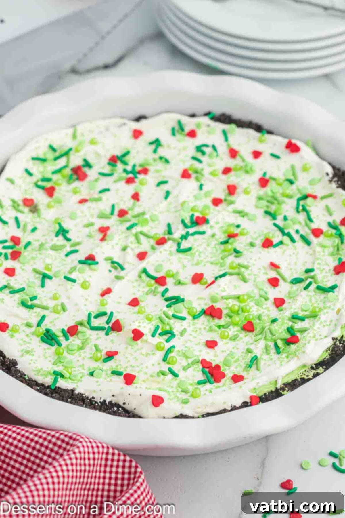 The Grinch's Heart-Melting Holiday Pie 12 A beautifully decorated whole Grinch pie, displayed on a festive serving plate, ready to be sliced and served at a holiday gathering.