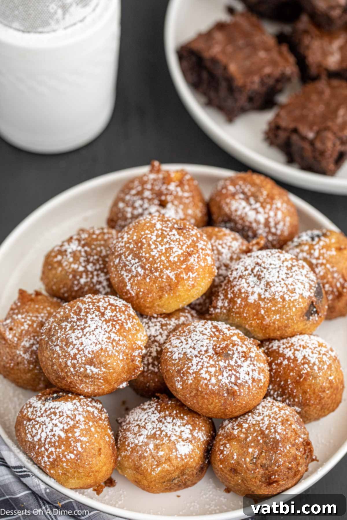 Decadent Deep-Fried Brownies 11 A tempting plate full of deep-fried brownie bites, glistening from the oil and generously dusted with white powdered sugar.