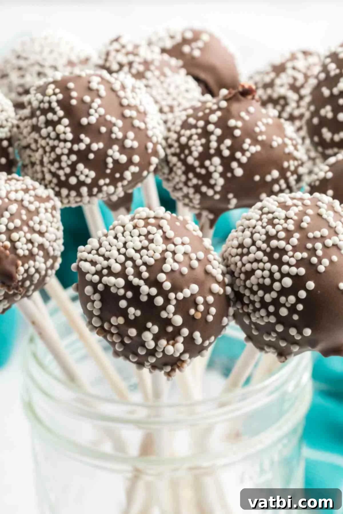 Chocolate cake pops topped with white sprinkles, elegantly presented in a mason jar.