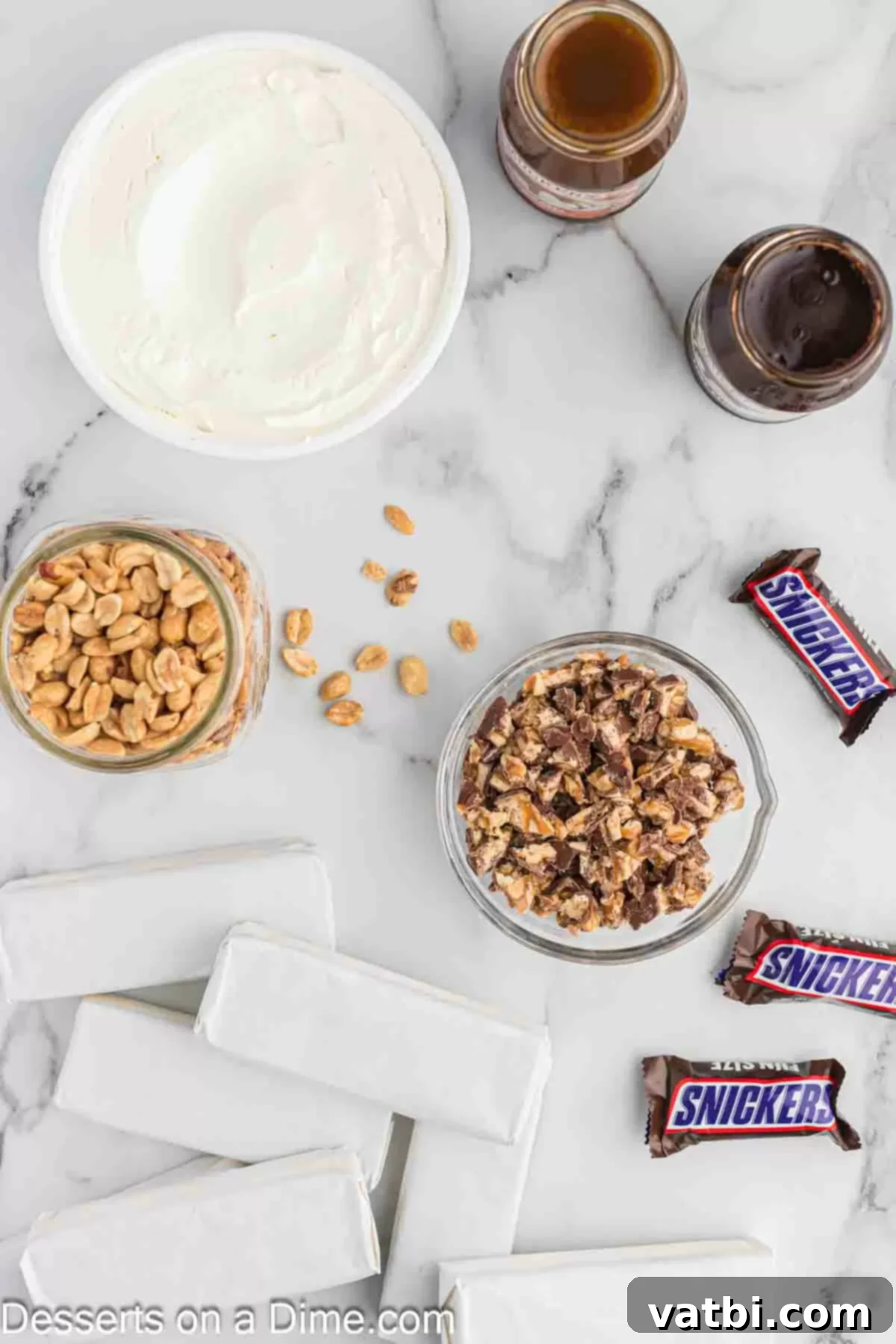 Decadent Snickers Ice Cream Cake 3 Ingredients for Snickers ice cream cake- ice cream sandwiches, hot fudge, caramel topping, whipped topping, snickers, peanuts.