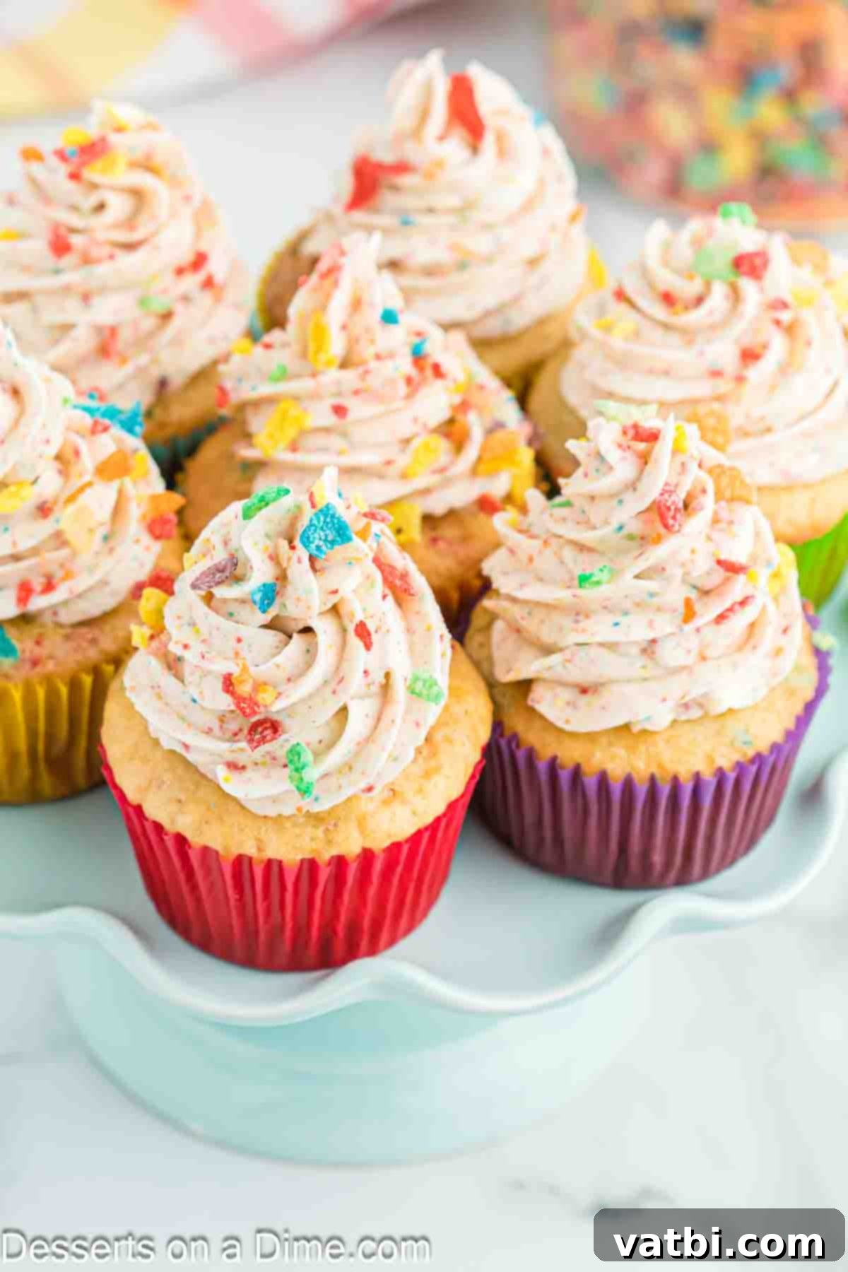 Rainbow Cereal Cupcakes 11 A platter of freshly baked and frosted Fruity Pebbles cupcakes, garnished with extra cereal.