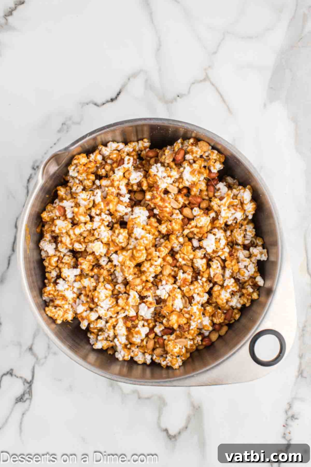 Homemade Cracker Jacks 8 Caramel poured over popcorn and peanuts in a large bowl.