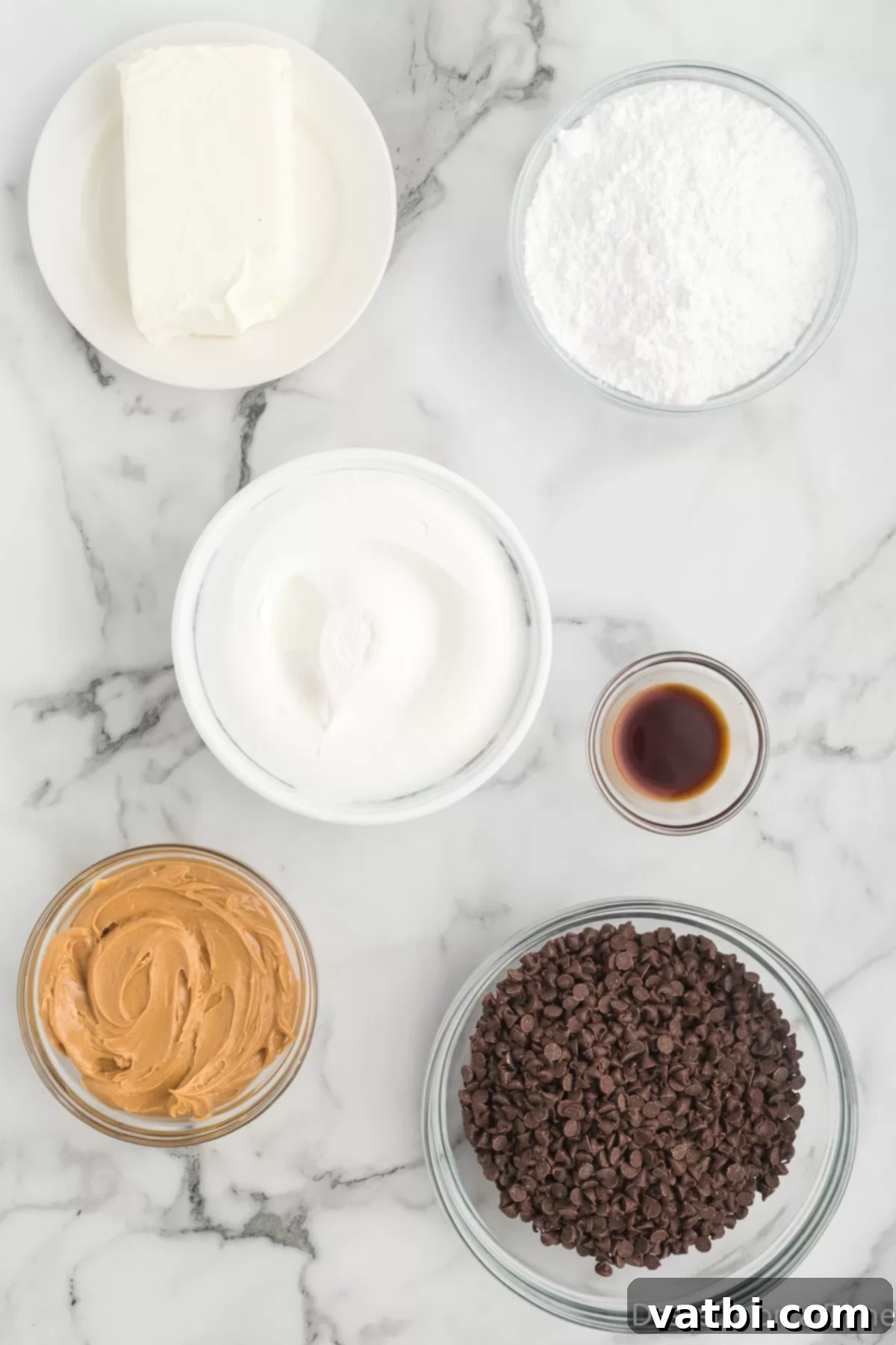 Decadent Buckeye Delight 3 Ingredients laid out for Buckeye dip: softened cream cheese, powdered sugar, a jar of creamy peanut butter, vanilla extract, a tub of whipped topping, and a bag of mini chocolate chips.
