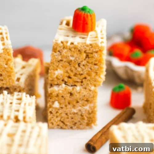 Pumpkin Spice Rice Krispie Treats decorated with small pumpkins and white chocolate.