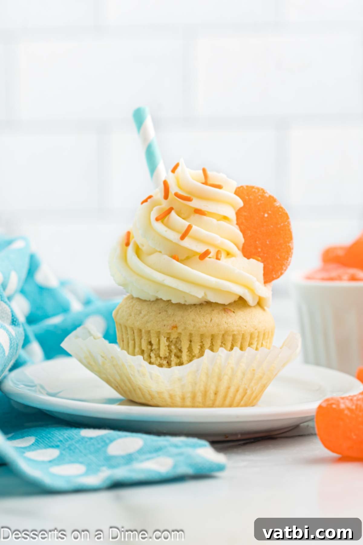 Velvet Orange Dream Cupcakes 12 A beautifully frosted orange creamsicle cupcake, garnished with orange zest, on a small plate.
