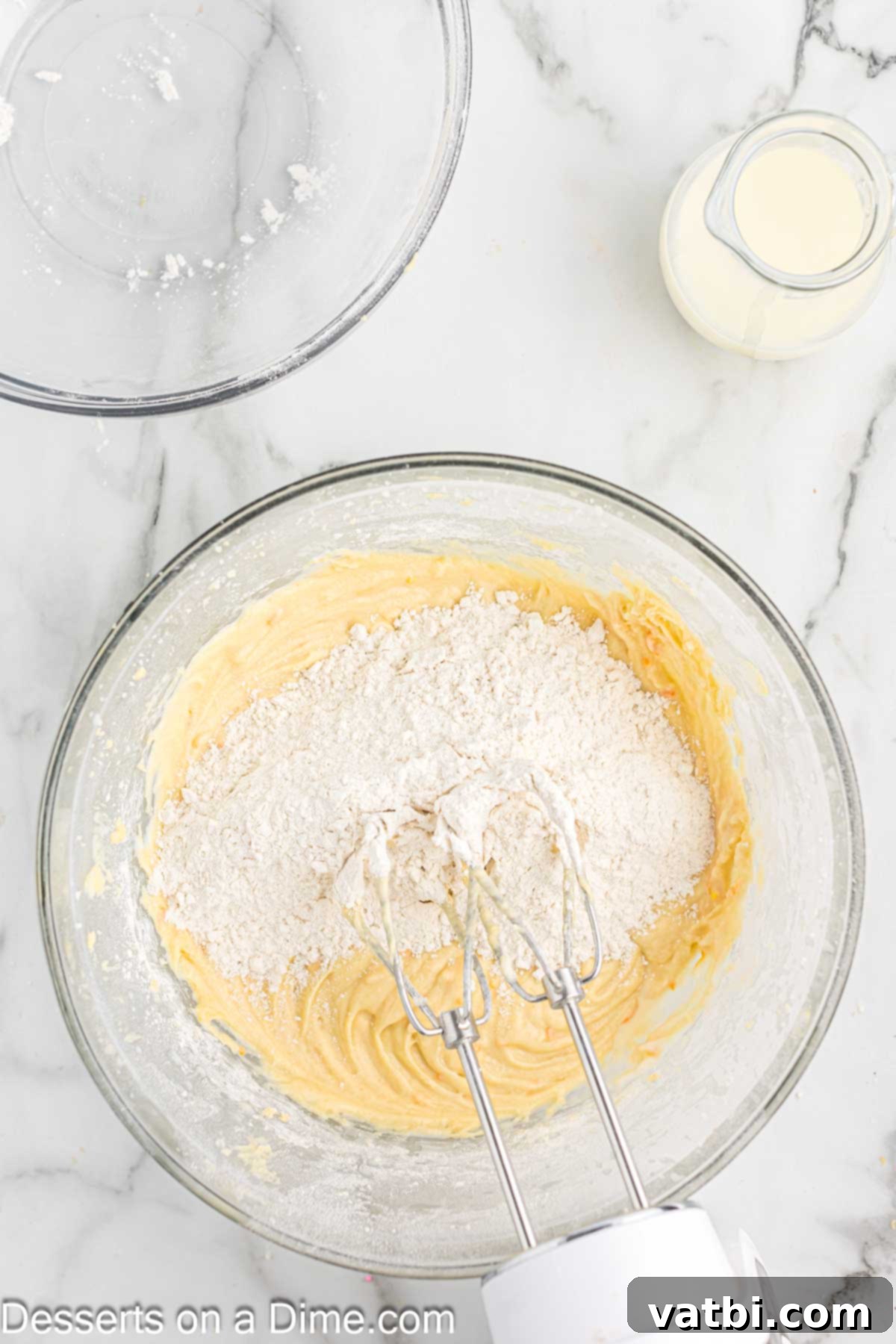 Velvet Orange Dream Cupcakes 6 Dry ingredients being gradually added to wet ingredients in a mixing bowl.