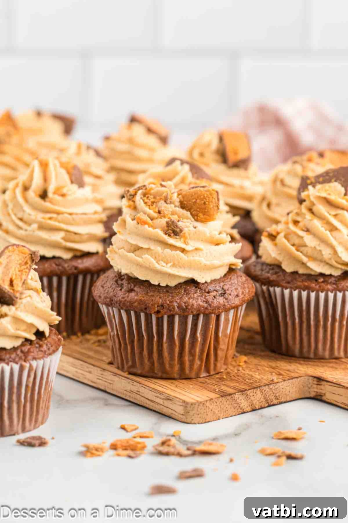Butterfinger Cupcakes 2 Butterfinger cupcakes ready to serve, showcasing the rich chocolate cake and peanut butter frosting with crushed candy topping.