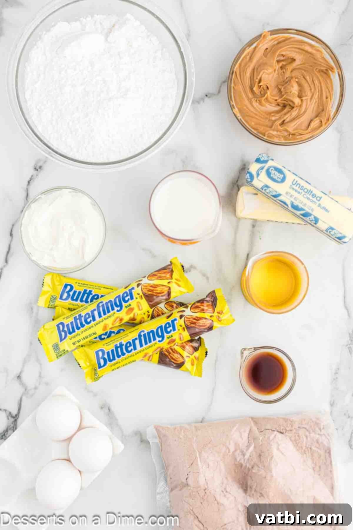 Butterfinger Cupcakes 3 A collection of ingredients laid out for making Butterfinger cupcakes, including cake mix, eggs, oil, milk, sour cream, vanilla, and candy bars.