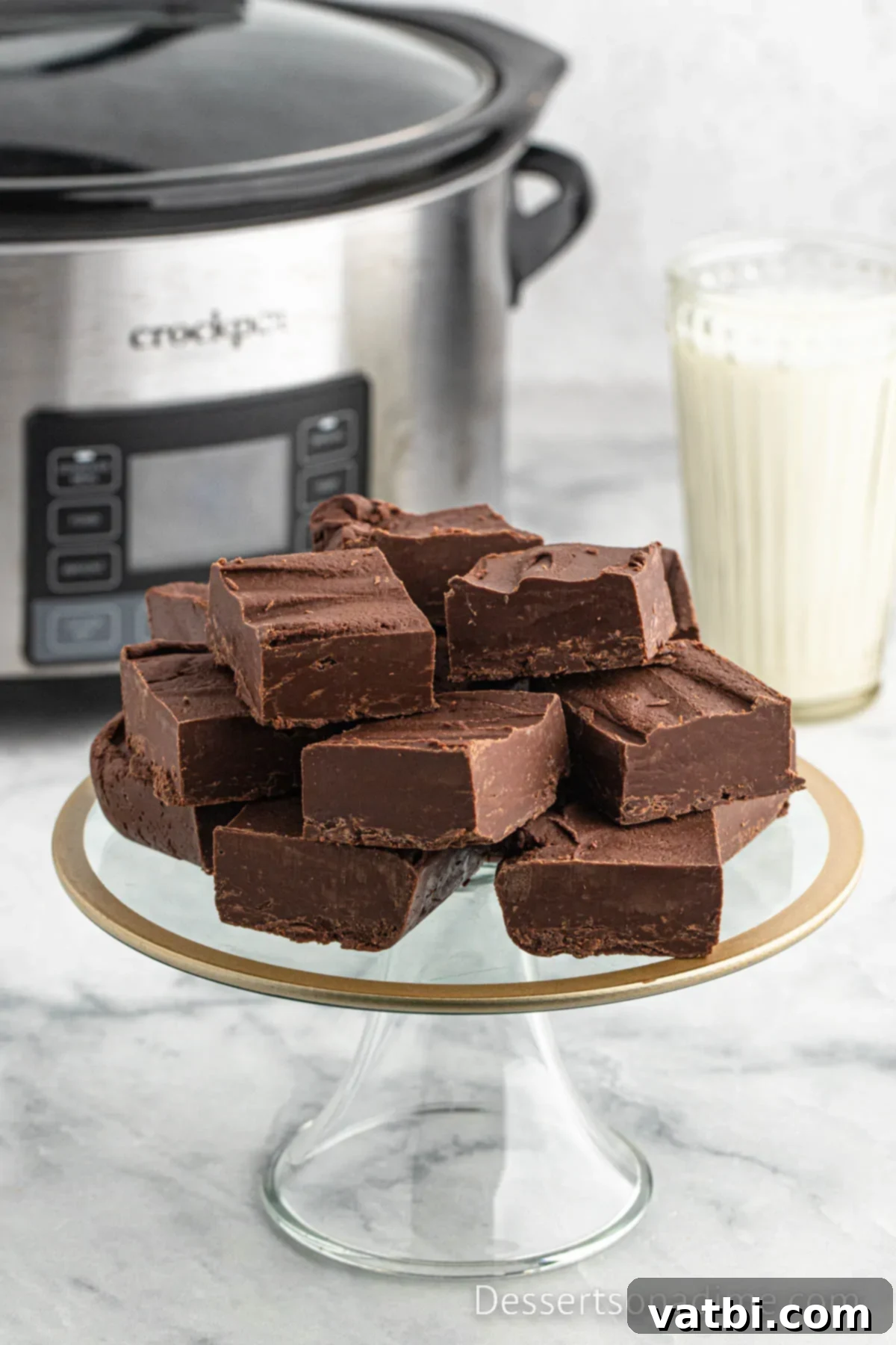 Crock Pot Fudge on a dessert stand, showcasing its smooth, rich texture and perfect square cuts.