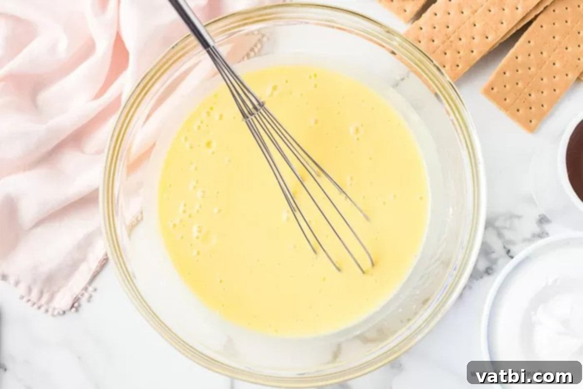 Effortless No-Bake Eclair Cake 2 Mixing the vanilla pudding mixture in a bowl with a whisk.