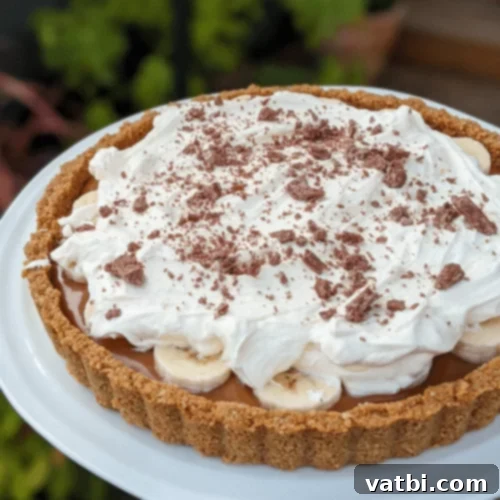 Thanksgiving Dessert Perfection: 35 Gluten-Free Pies 23 A glorious Gluten-Free Banoffee Pie, expertly crafted with layers of caramel, bananas, and whipped cream, presented on a cake stand.