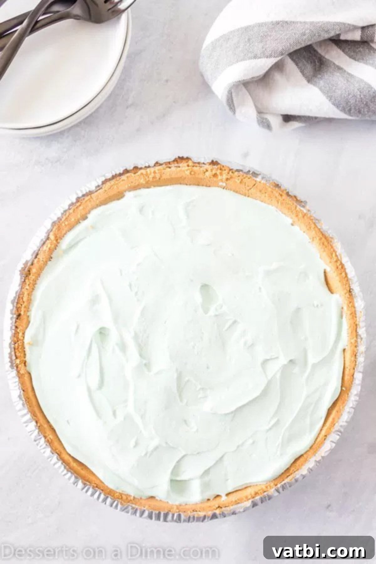 Kool Aid Pie Ready for Chilling in the Refrigerator A freshly prepared Kool-Aid pie, with its smooth, colorful filling spread evenly into a graham cracker crust, placed on a counter, ready to be transferred to the refrigerator for chilling and setting.