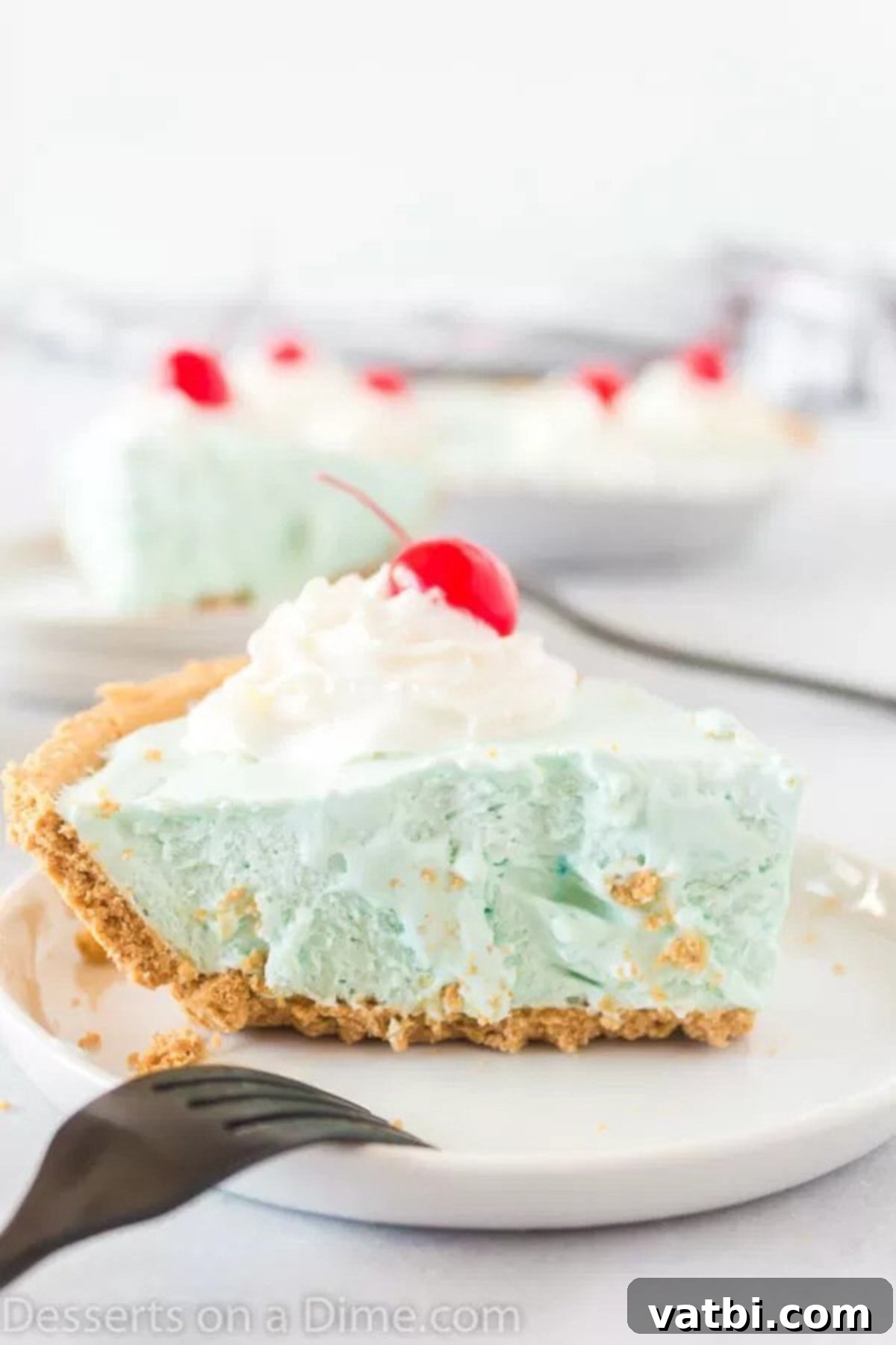 Delicious Slice of No-Bake Kool Aid Pie Ready to Enjoy A close-up of a perfectly sliced Kool-Aid pie on a white plate, revealing its smooth, vibrant blue filling and crispy graham cracker crust. The slice sits ready for enjoyment.
