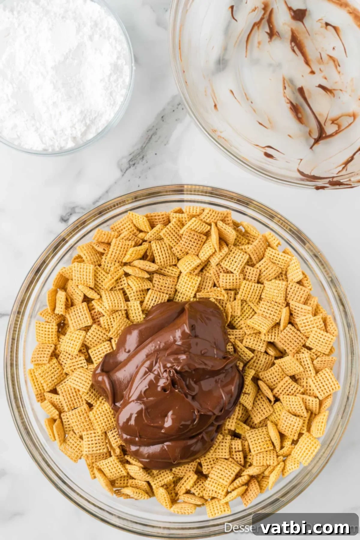 S'mores Campfire Crunch 6 Melted chocolate and peanut butter mixture being poured over Chex cereal in a large bowl.