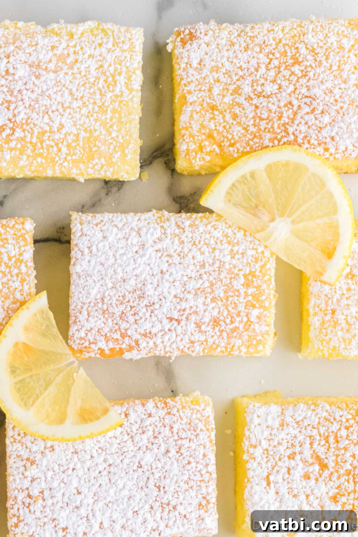 Lemon bars cut into squares, dusted with powdered sugar, ready to serve.