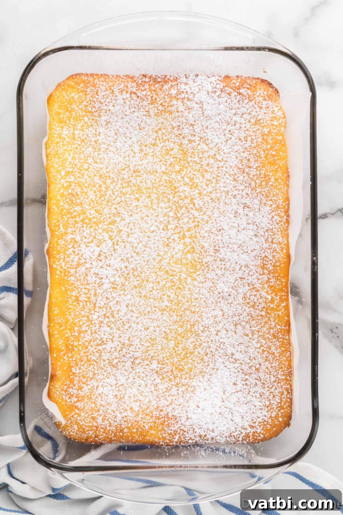Powdered sugar being sprinkled over baked lemon bars.