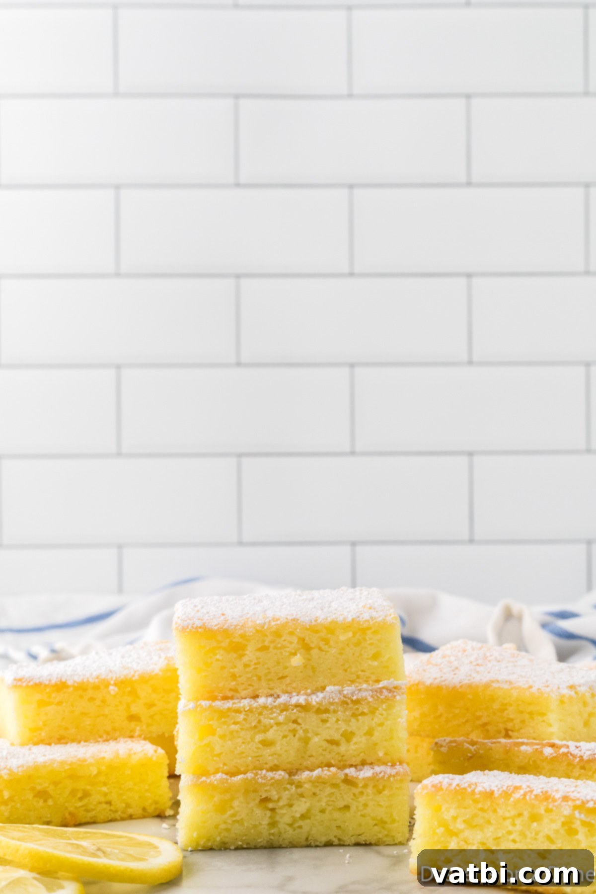 Lemon bars perfectly cut into squares and arranged on a serving plate.