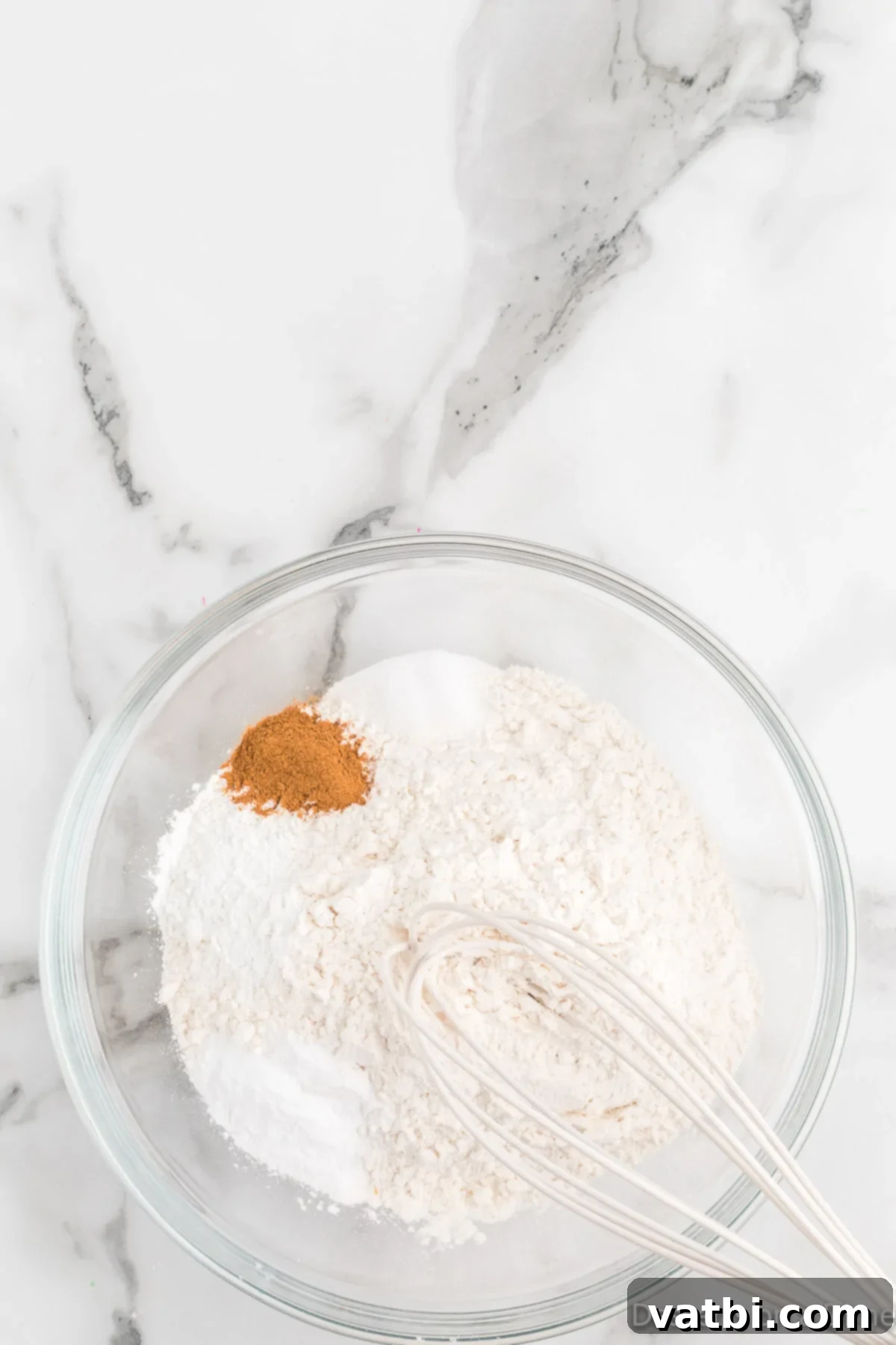 Festive Ranch Cookies 4 Combining the dry ingredients in a bowl: all-purpose flour, baking soda, baking powder, ground cinnamon, and salt, being whisked together thoroughly.
