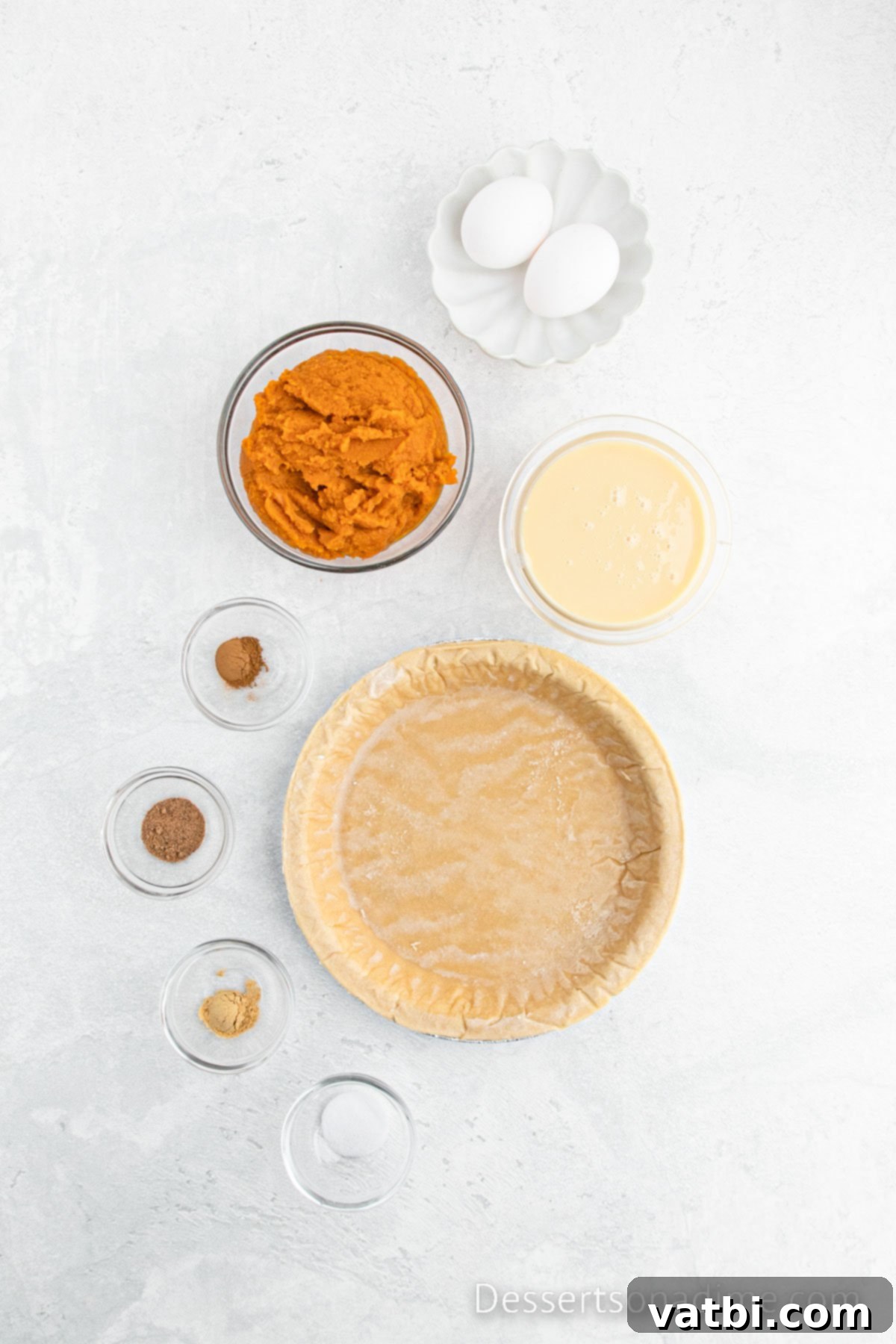 A collection of essential ingredients for making pumpkin pie, including an unbaked pie crust, a can of pumpkin puree, a can of Eagle Brand sweetened condensed milk, eggs, ground ginger, and ground nutmeg, arranged neatly for cooking.