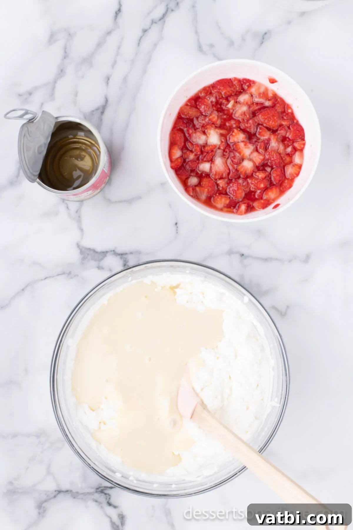 Easy No-Churn Strawberry Ice Cream 6 Sweetened condensed milk is carefully poured into the whipped cream mixture in a large mixing bowl.