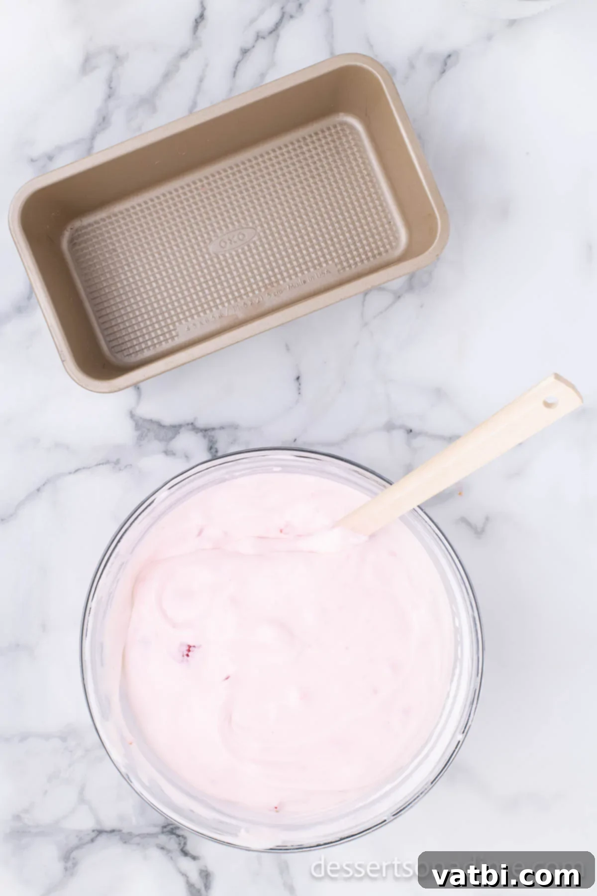 Easy No-Churn Strawberry Ice Cream 8 A rubber spatula is used to gently fold the strawberry mixture into the creamy ice cream base until just combined.