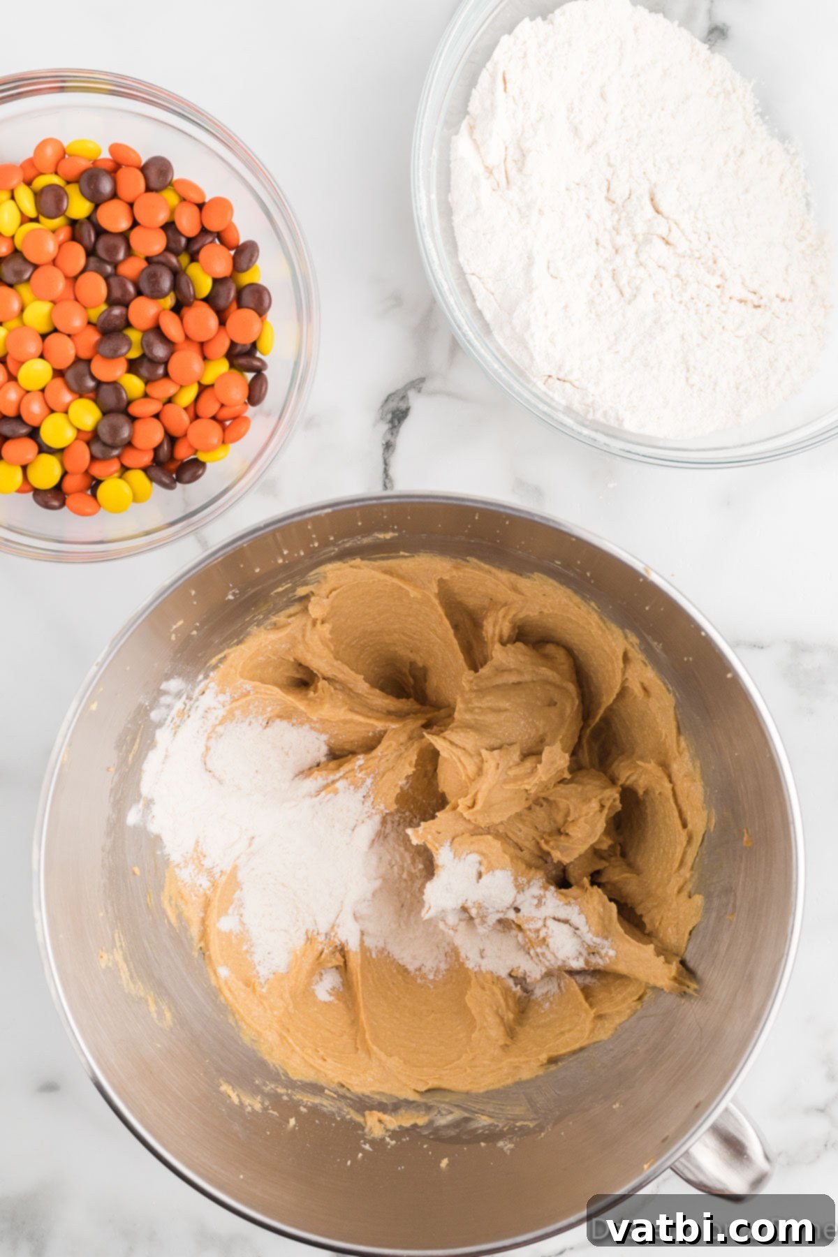 Reese's Pieces Peanut Butter Perfection 7 Flour mixture slowly added to the peanut butter cookie dough in a mixer.