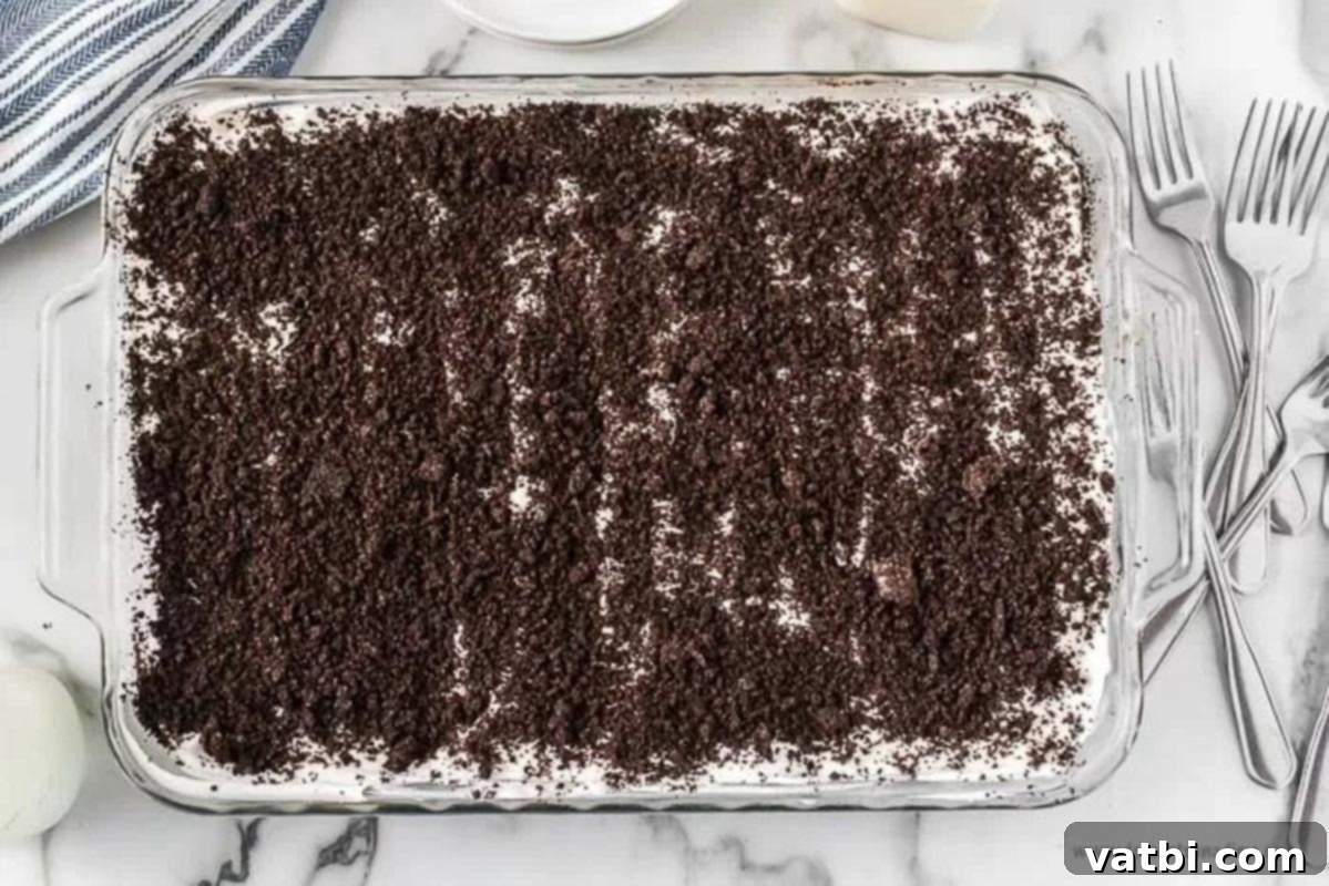 Decadent No-Bake Oreo Lasagna 7 Baking dish topped with whipped cream and reserved Oreo crumbs