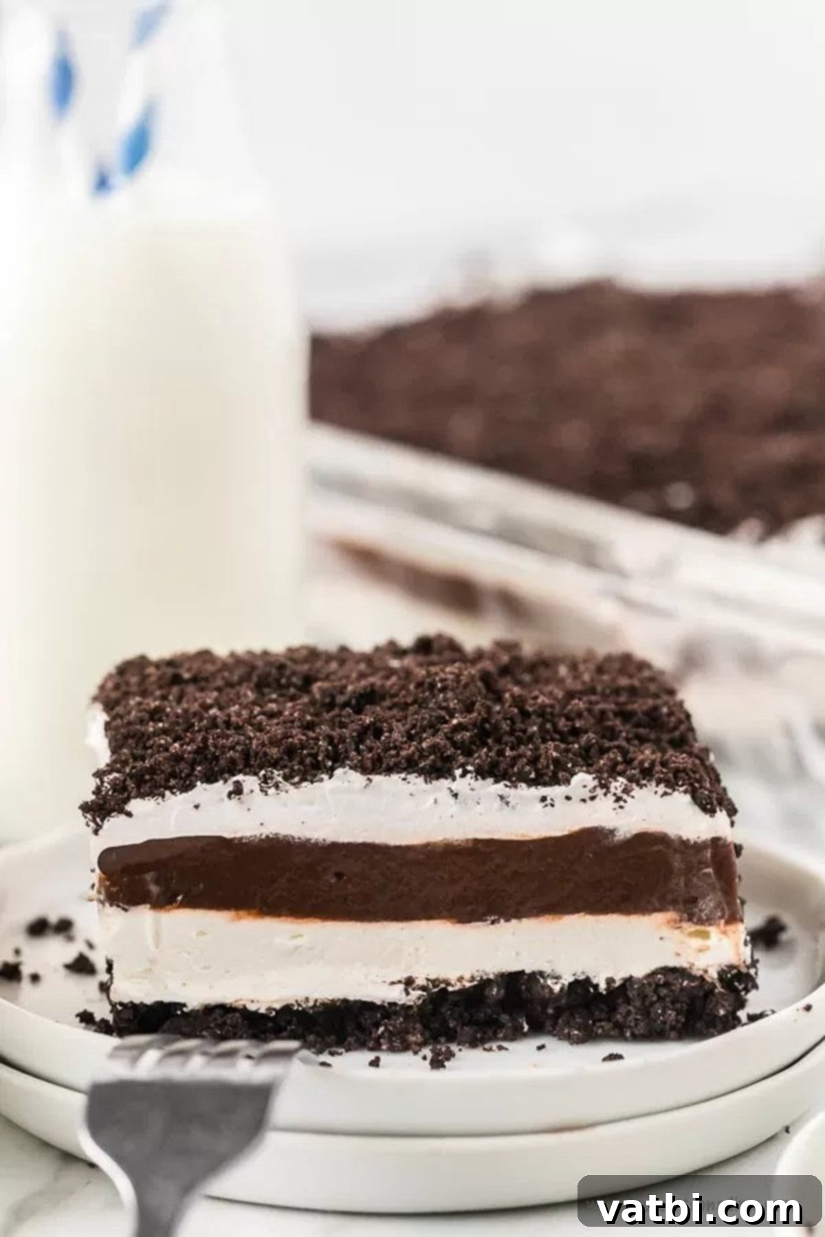Layers of oreo cookies, pudding and an amazing cream cheese layer make this Oreo Lasagna Recipe heavenly. It is the perfect no bake dessert and so easy. Chocolate fans will love this chocolate oreo lasagna. #dessertonadime #oreolasagnarecipe #oreolasagnarecipecoolwhip Chocolate Lasagna sliced and served on a plate, ready to enjoy