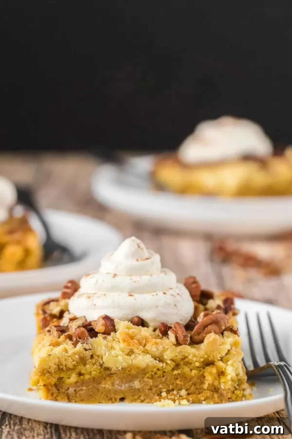 Delicious Slice of Pumpkin Pie Cake with Whipped Cream Slice of pumpkin pie cake on a plate topped with whipped cream and a sprinkle of cinnamon.