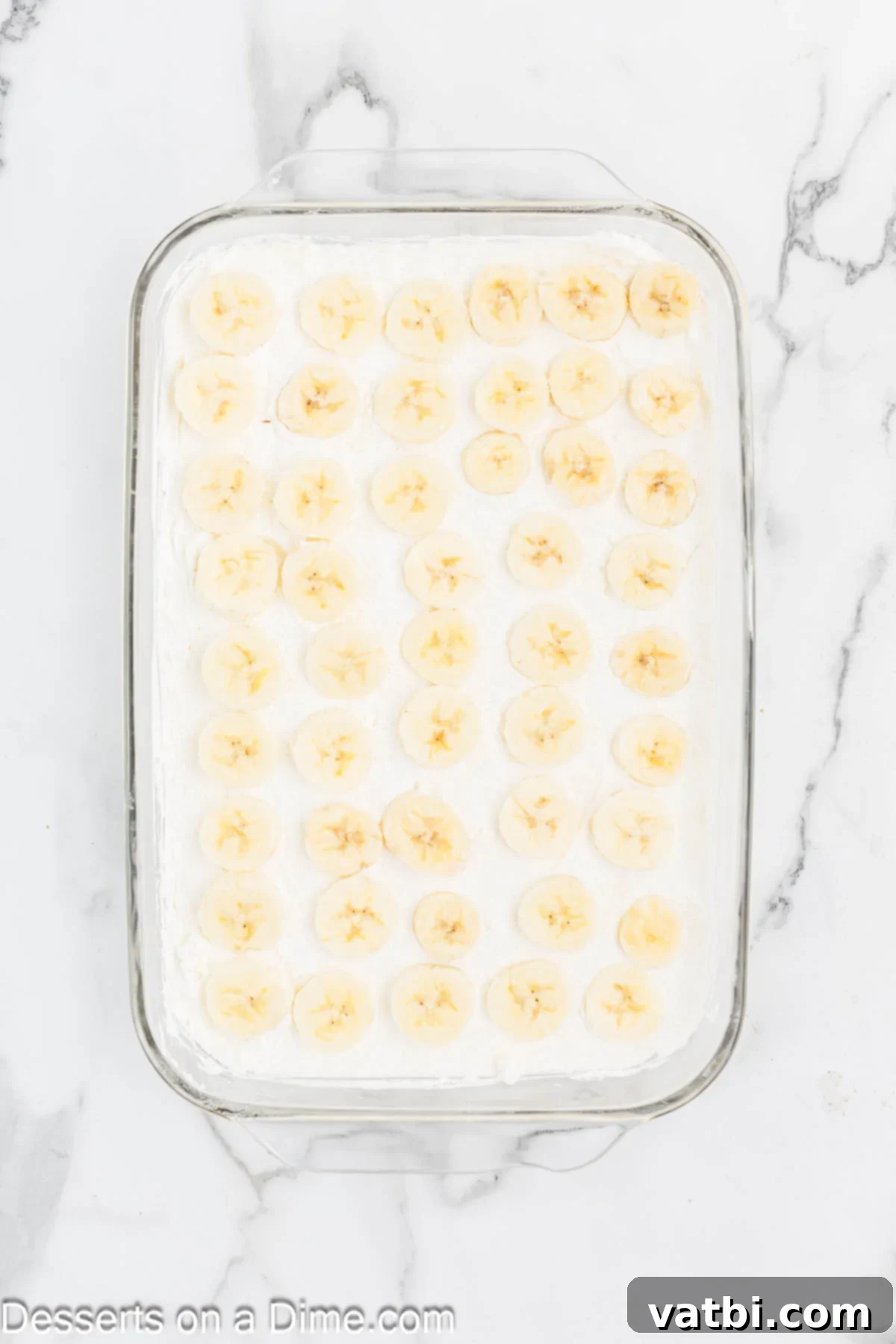 Banana slices on top of cream cheese layer in pan. 
