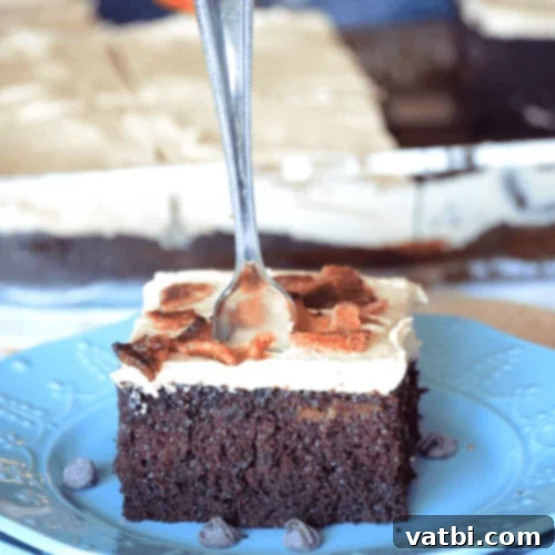Slice of Chocolate Peanut Butter Bacon Cake with creamy frosting and bacon bits.