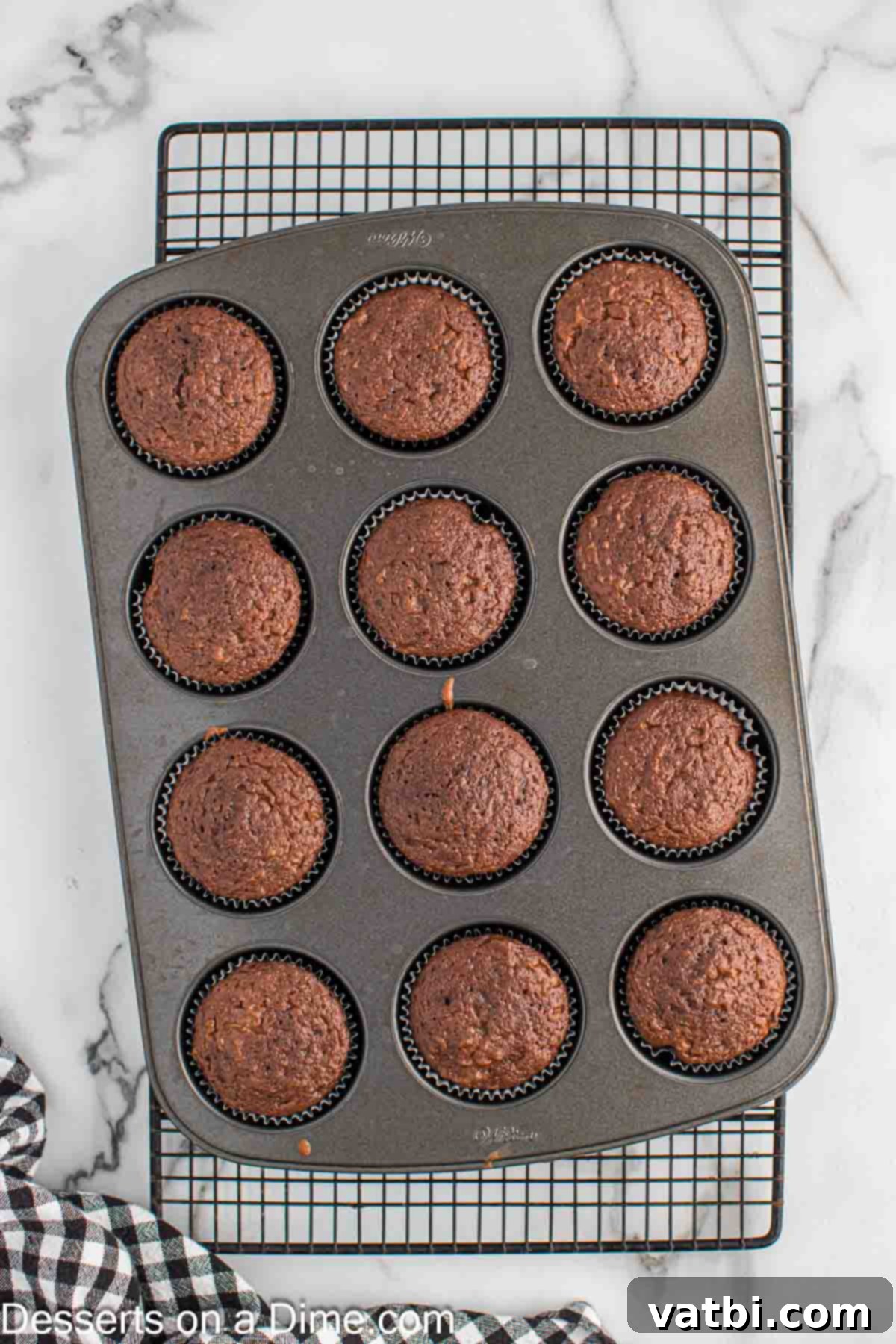 Carved Pumpkin Cupcakes 5 Freshly baked cupcakes cooling in the muffin pan on a wire rack.