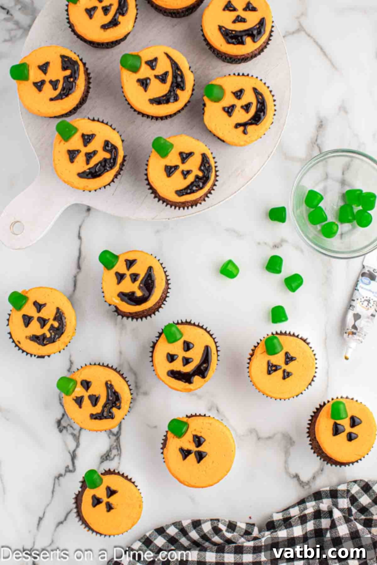 Carved Pumpkin Cupcakes 9 Jack-O-Lantern faces drawn with black decorator gel and green gumdrop stems added to each frosted cupcake.