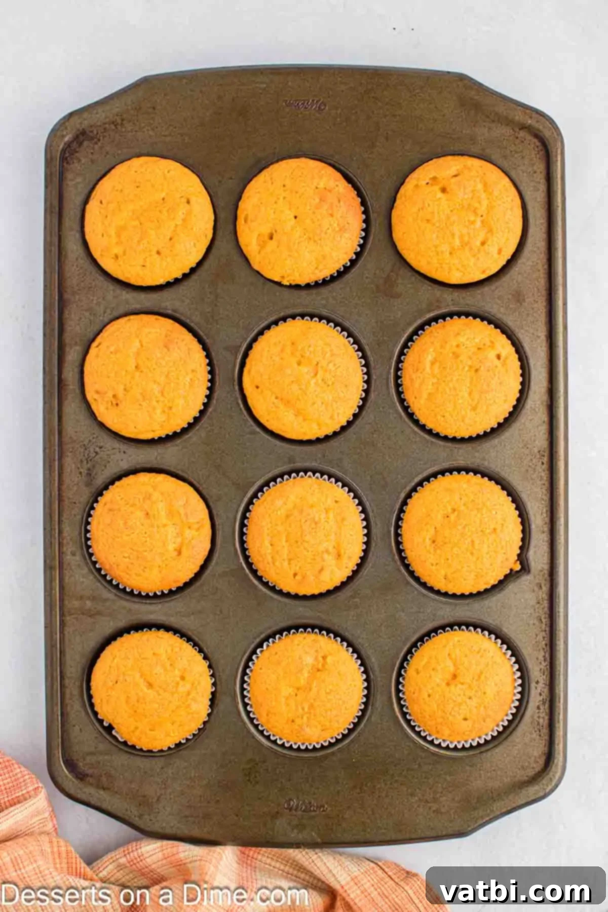 Freshly baked butterscotch cupcakes cooling in a muffin tin on a wire rack.